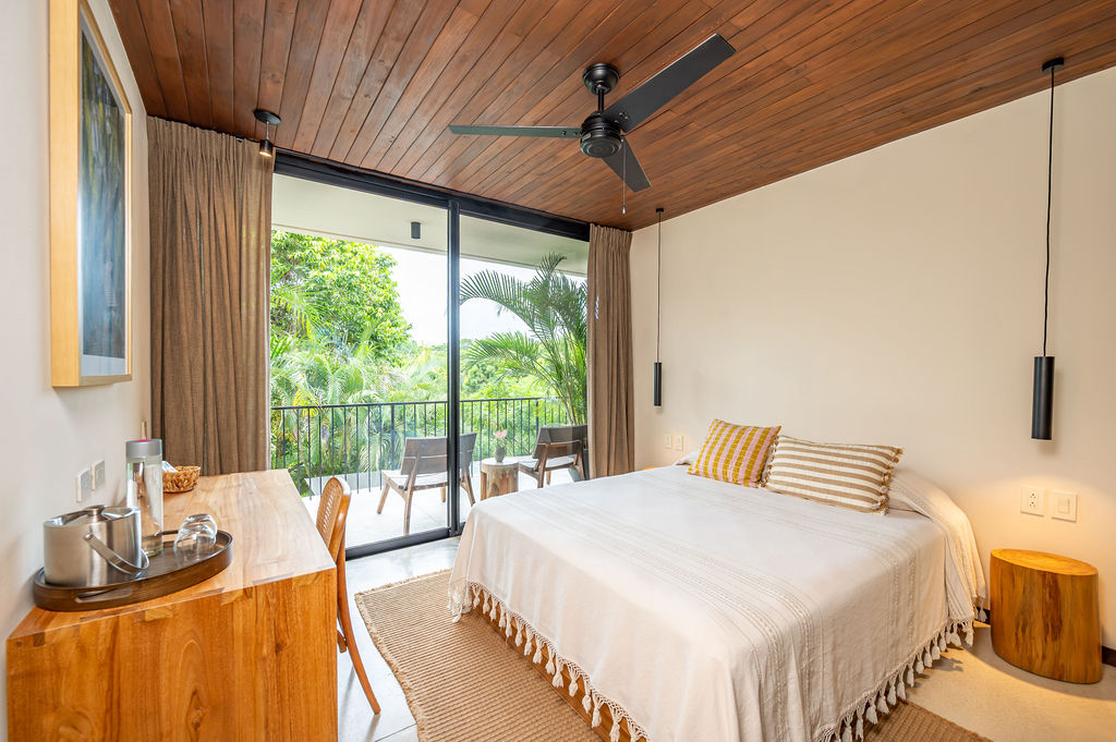 Suite Four — queen bed with balcony chairs facing the treetops