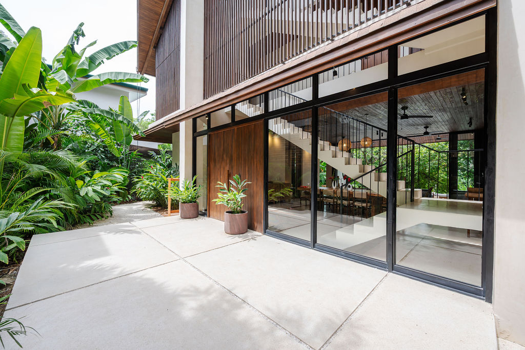 Casa Aguacate's A-frame facade and glass great room wall framed by jungle