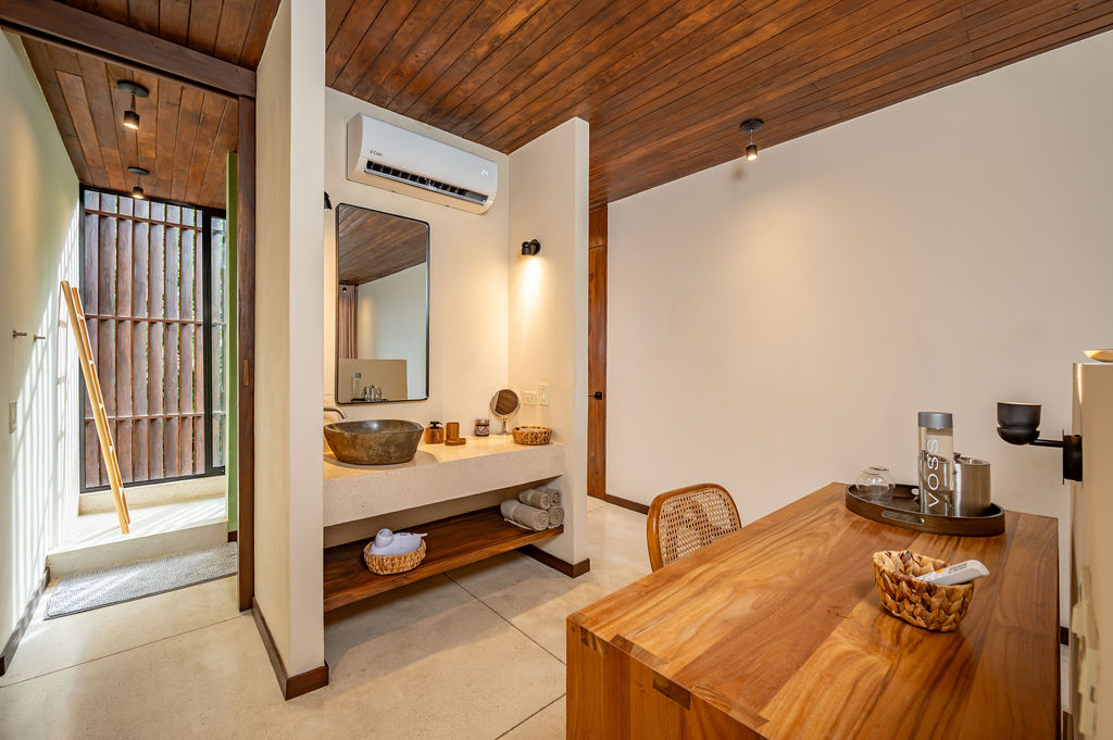 Suite Five vanity zone with stone basin, rolled towels and the screened shower court beyond